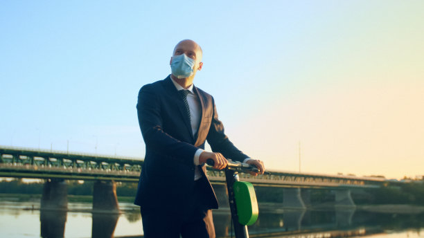 商人戴着面具骑摩托车。市内交通安全。河畔图片下载