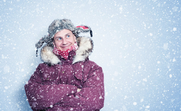 快乐冻人穿着红色冬衣站在墙边，雪花四处飘落图片下载