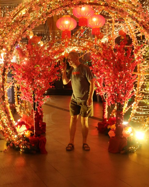 一名白人成年男子正在欣赏由红色和金色装饰的中国新年拱门图片下载