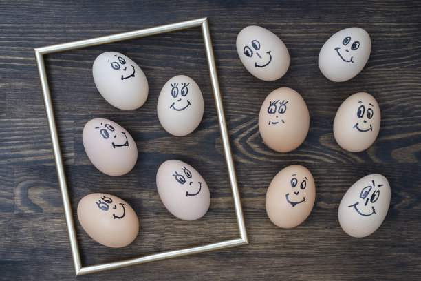 图片的金色框架和许多有趣的鸡蛋微笑在黑暗的木墙背景。鸡蛋家庭情感面部肖像。概念有趣的食物图片下载