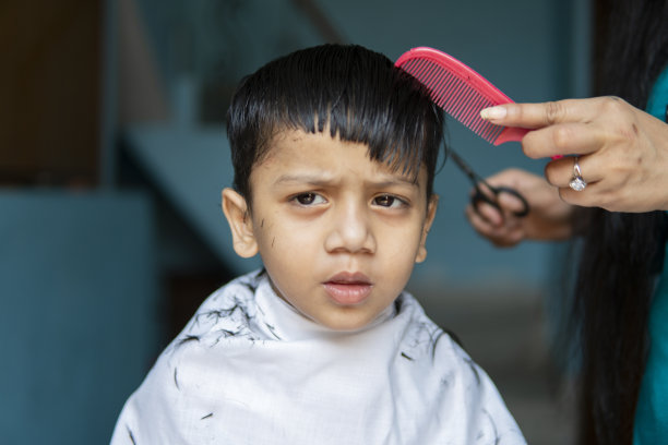 母亲在家给孩子剪头发。图片下载