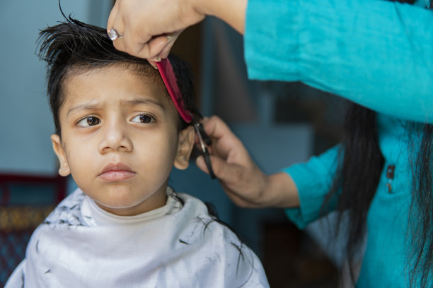 母亲在家给孩子剪头发。图片下载