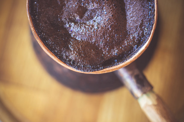 天然咖啡与厚泡沫，煮铜cezve在古典方式，在木制背景，微距照片。图片下载