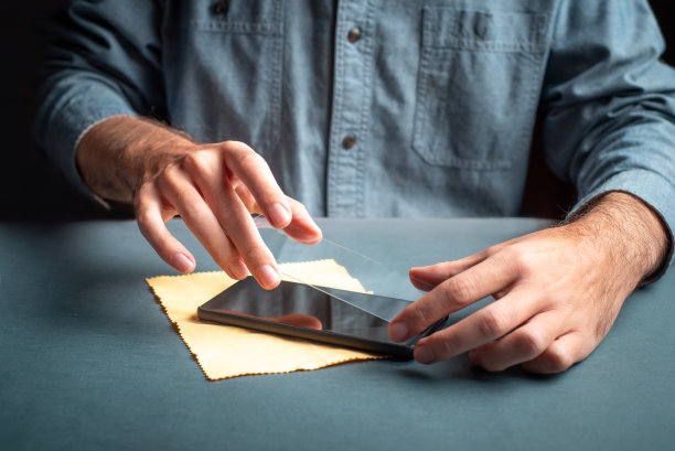 男子将防刮保护玻璃应用到智能手机屏幕近距离图片下载