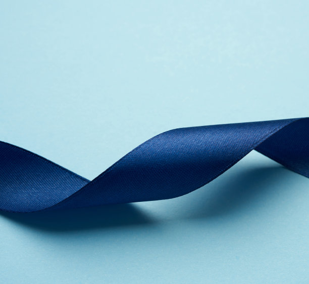在浅蓝色背景上卷曲的深蓝色丝绸缎带图片下载