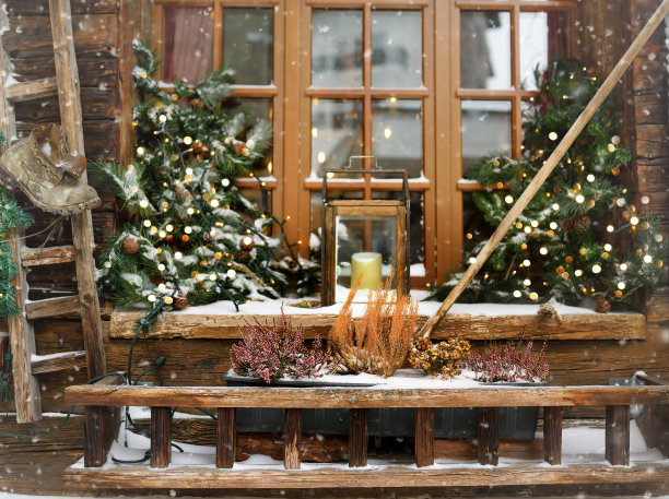 时尚的圣诞装饰靠近窗户-冷杉树枝上的花环灯和灯笼与大蜡烛在欧洲的一个小镇的街道上。冬季节日街道的装饰和照明图片下载