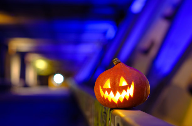 万圣节南瓜在黑暗中的蓝色工业抽象背景。模糊的彩灯。图片下载