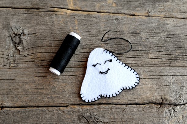 如何制作手工万圣节鬼饰品。两块白色的毛毡缝着黑色的线。的一步。儿童工艺指导。特写镜头。前视图。缝纫项目万圣节容易diy图片下载