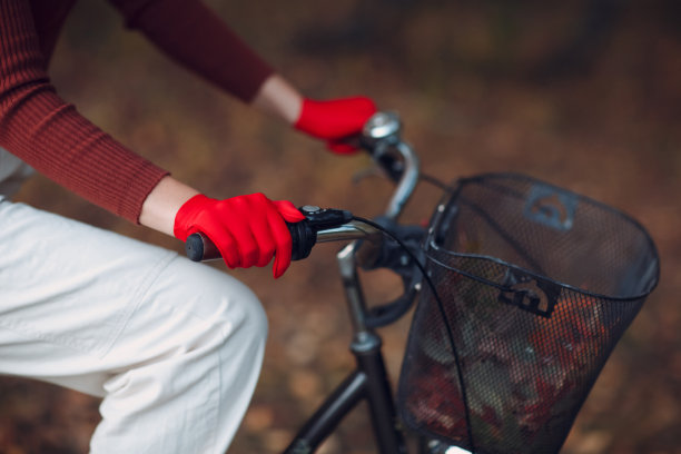 在秋天的公园里，年轻的女子戴着红色的手套和面罩骑着自行车图片下载