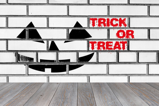 万圣节的杰克灯笼脸和trick or treat的文字画在白色的砖墙上图片下载