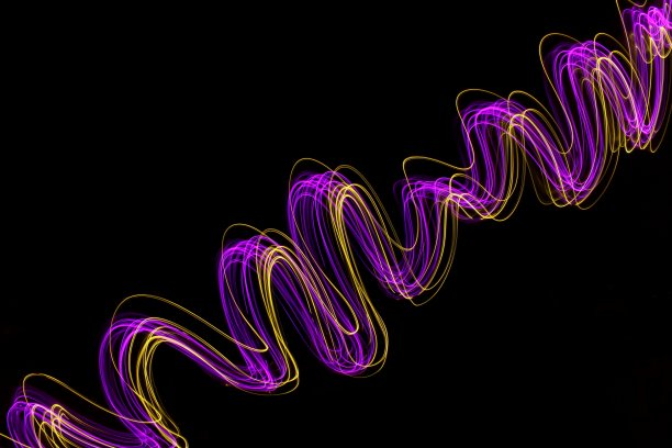 长时间曝光的照片，霓虹粉色和金色在抽象的漩涡，平行线模式，以黑色背景。光绘摄影。图片下载