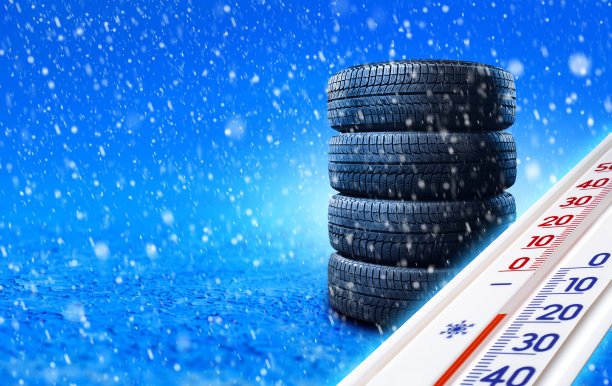 新的冬季轮胎堆放在雪地上，温度计显示负温度。带有拷贝空间的横幅。图片下载