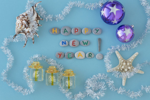 用五颜六色的字母在灰色的海石、贝壳、星星和长长的银箔上刻下新年的碑文。图片下载