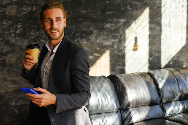 一个穿着西装拿着电话喝着咖啡的人。图片下载