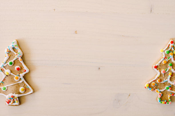 两个姜饼饼干的形状的圣诞树，装饰釉和彩色的点缀，在白色油漆木材纹理。放置文本在中心。图片下载
