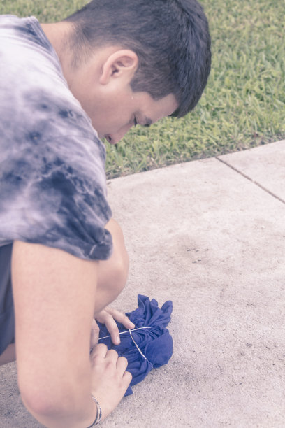 在新冠病毒期间，年轻的拉丁裔男子在美国用扎染工艺制作鲜艳的T恤。图片下载