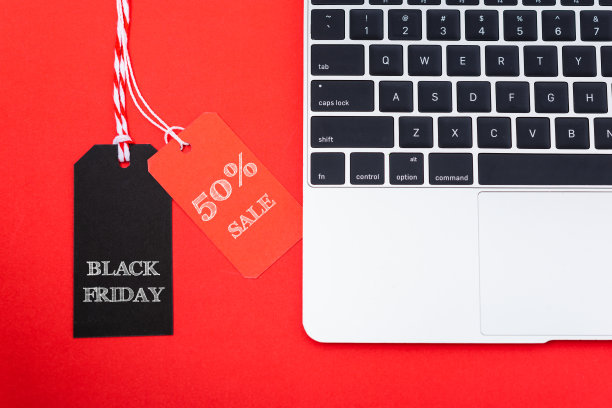 网上购物营销，顶视图的工作空间与黑色星期五销售50%的文本红色和黑色标签附近的笔记本电脑图片下载