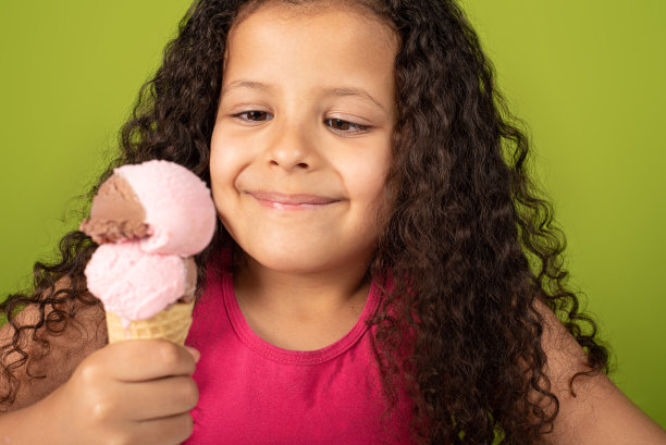 快乐的孩子与两球冰淇淋甜筒与绿色的背景，选择性的焦点。图片下载