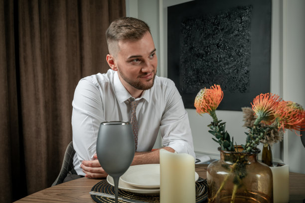 一个年轻英俊的男人坐在家里的浪漫晚餐图片下载