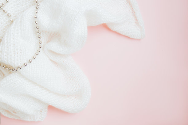 白色针织面料和银色的珠子在粉红色的背景图片下载