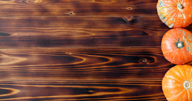 俯视图上三个装饰性的黄色南瓜排在深色木制桌子的背景图片下载