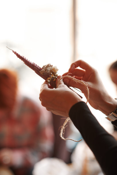 DIY蜡烛制作过程。女人做装饰蜡蜡烛和装饰干花，手的特写图片下载