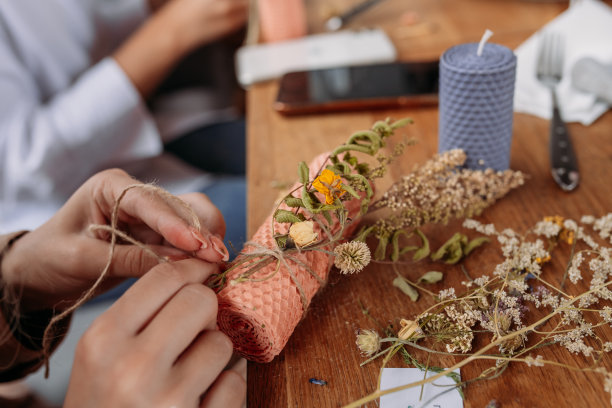 DIY蜡烛制作过程。女人做装饰蜡蜡烛和装饰干花，手的特写图片下载