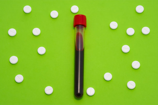 绿色背景上是带血的试管，周围是白色的圆点图案。概念艺术照片用于医学，血液学，血液疾病的诊断图片下载