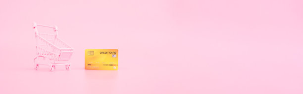 购物和支付概念从小手推车和信用卡在粉红色柔和的颜色背景。网络横幅的尺寸。图片下载