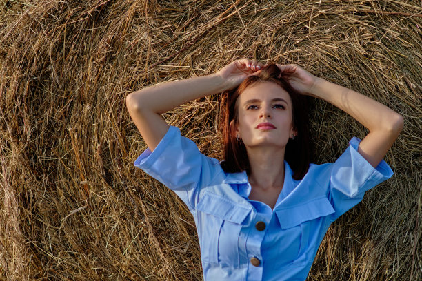 一个穿着蓝裙子的女孩，在碧绿的田野里，靠近一个干草堆图片下载