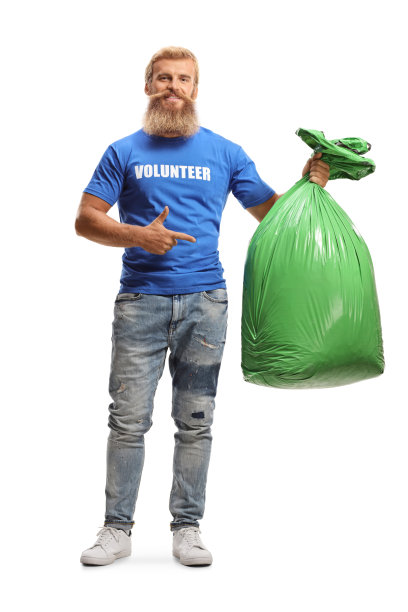 一个男性志愿者拿着一个绿色塑料垃圾袋并指着它的全身像图片下载