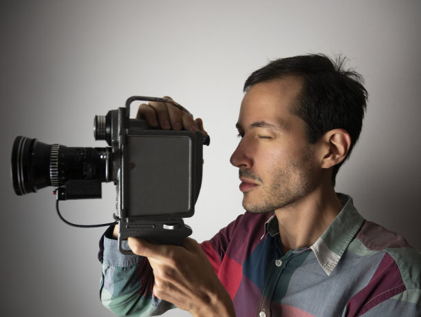 用老式摄像机拍摄的摄影师。模拟技术。拍电影。电影制作。老式电影摄影机。图片下载