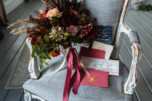 灰色的椅子上放着一束亮紫红色的花束，上面写着字母。复古风格图片下载