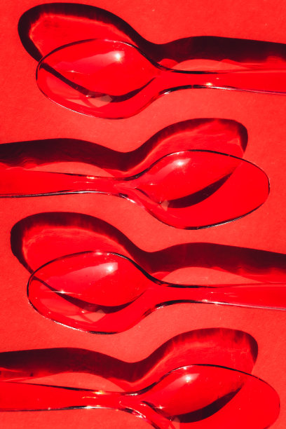 一次性塑料勺，红色背景，对比鲜明的阴影图片下载