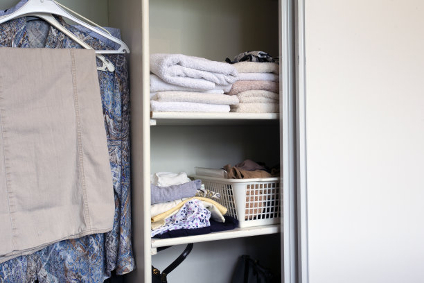 满壁橱的衣服和毛巾堆放在白色的木制壁橱，组织和存储图片下载
