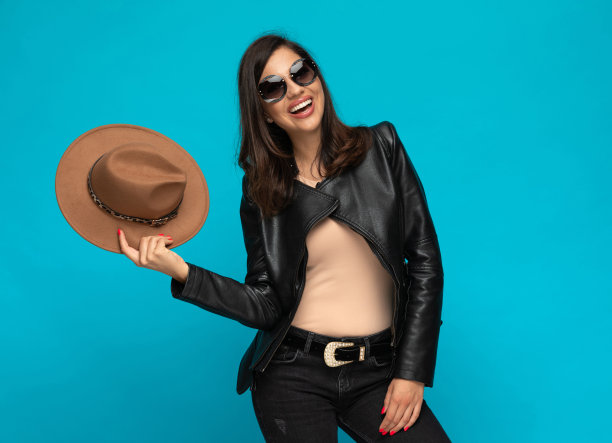 开朗随意的女人拿着帽子笑着，戴着太阳镜图片下载