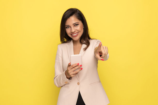 快乐的年轻女商人一边看电子邮件一边微笑图片下载