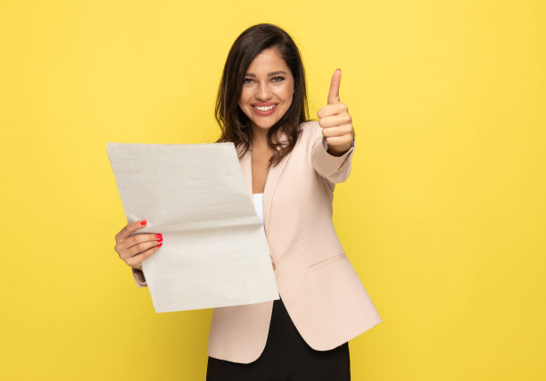 快乐的小女孩一边看报纸一边竖起大拇指图片下载