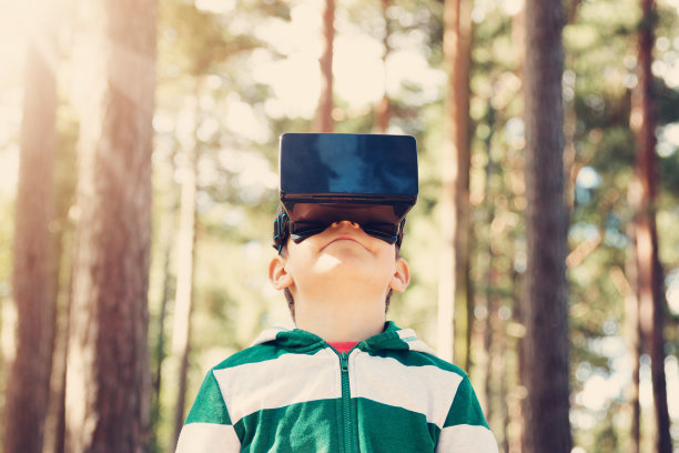 孩子戴着虚拟现实眼镜站在森林里图片下载