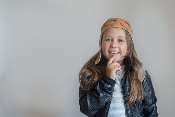 戴着头盔的快乐小女孩，背景是灰色图片下载