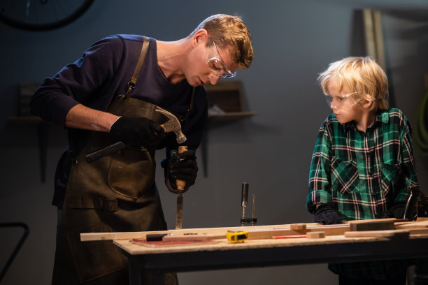 一位年轻的父亲在车库里教他的儿子木工的基本知识图片下载