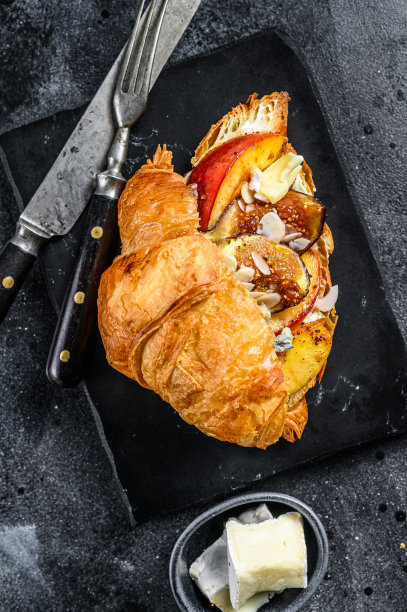 法式羊角面包配布里奶酪，桃子和无花果。黑色木制背景。顶视图ё图片下载