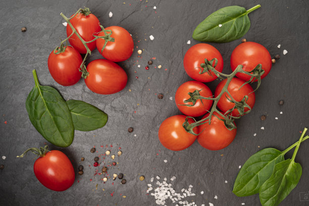 成熟的番茄和香料放在一块黑色板板上图片下载