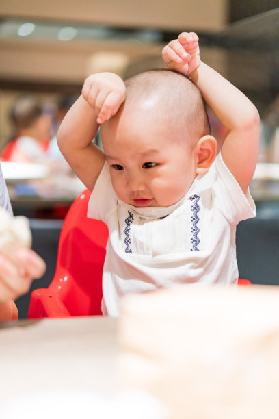 一个男婴坐在餐厅的餐椅上图片下载