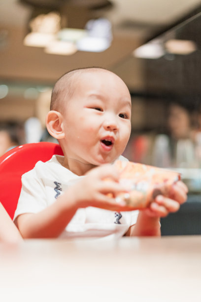 一个男婴坐在餐厅的餐椅上图片下载