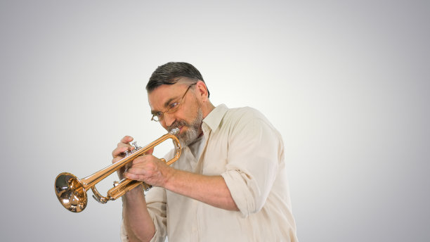 戴眼镜的老人在渐变背景上吹小号图片下载