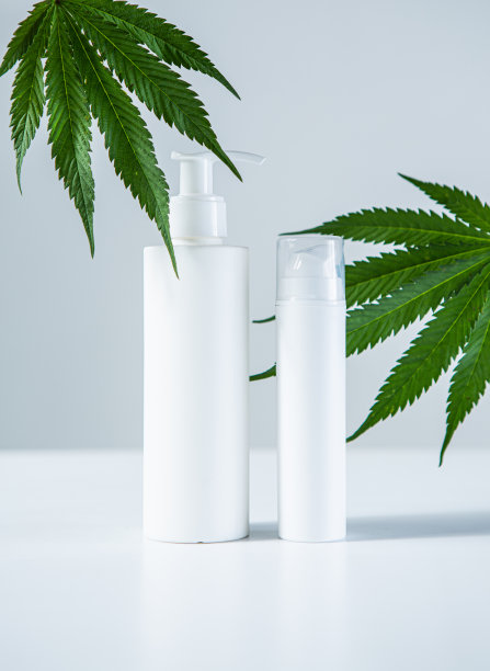 白色空白化妆瓶和麻叶在灰色工作室背景，模拟。生物有机产品图片下载