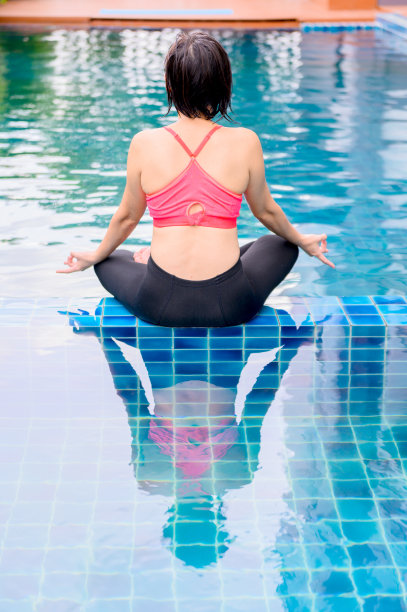 亚洲妇女瑜伽呼吸和冥想独自在家里的游泳池。为了健康，户外运动和锻炼。图片下载