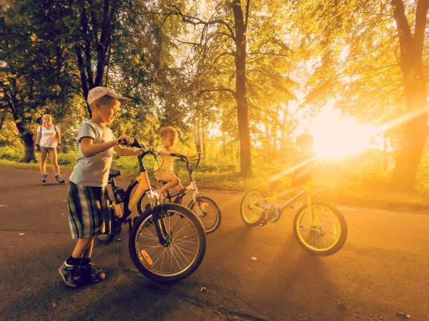 夕阳下在路上骑行的自行车家庭图片下载
