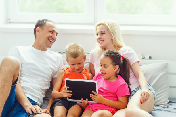 一个狂喜的家庭和两个孩子在触摸板上看着一些有趣的东西图片下载